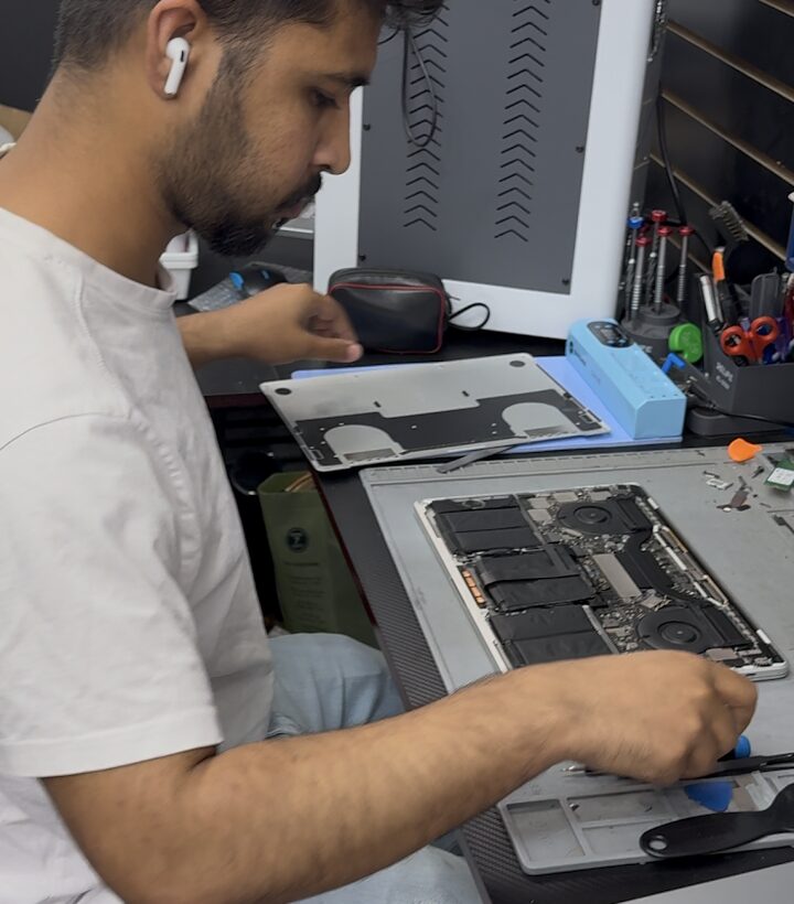 Technician working on an opened MacBook at the repair bench in Long Island City